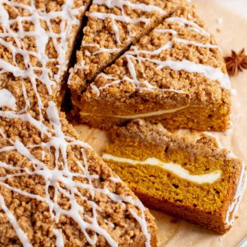 slices of pumpkin crumb cake with white icing on a cutting board next to an orange slice