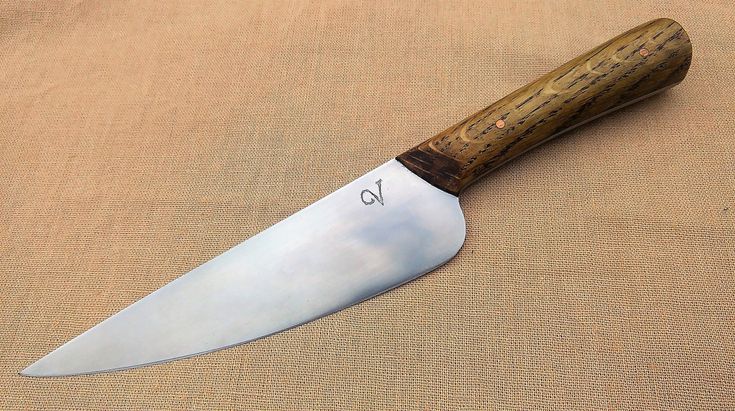 a large knife with a wooden handle sitting on top of a tan cloth covered surface