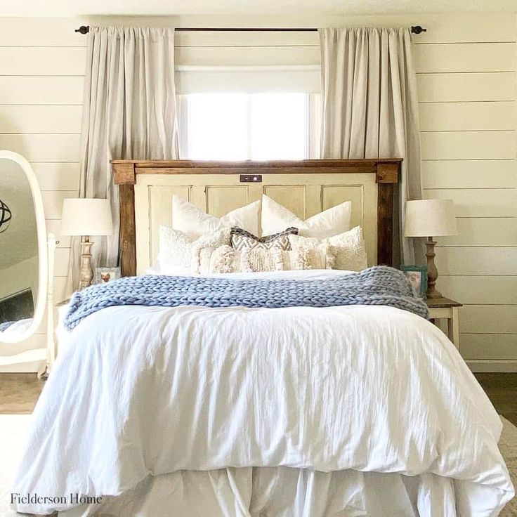 a bed with white linens and pillows in a bedroom next to a large mirror