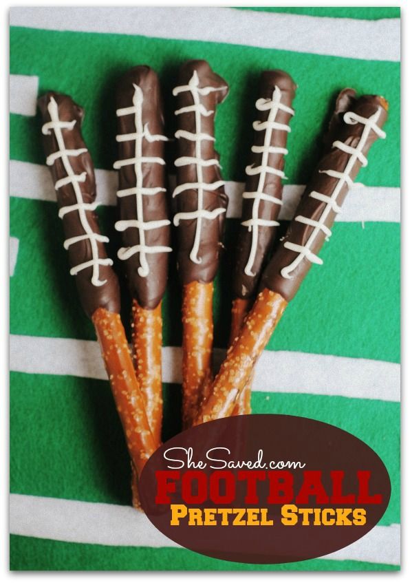 four pretzel sticks decorated like footballs on a green and white striped towel