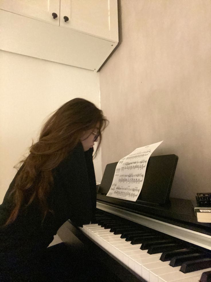 a woman sitting at a piano playing music