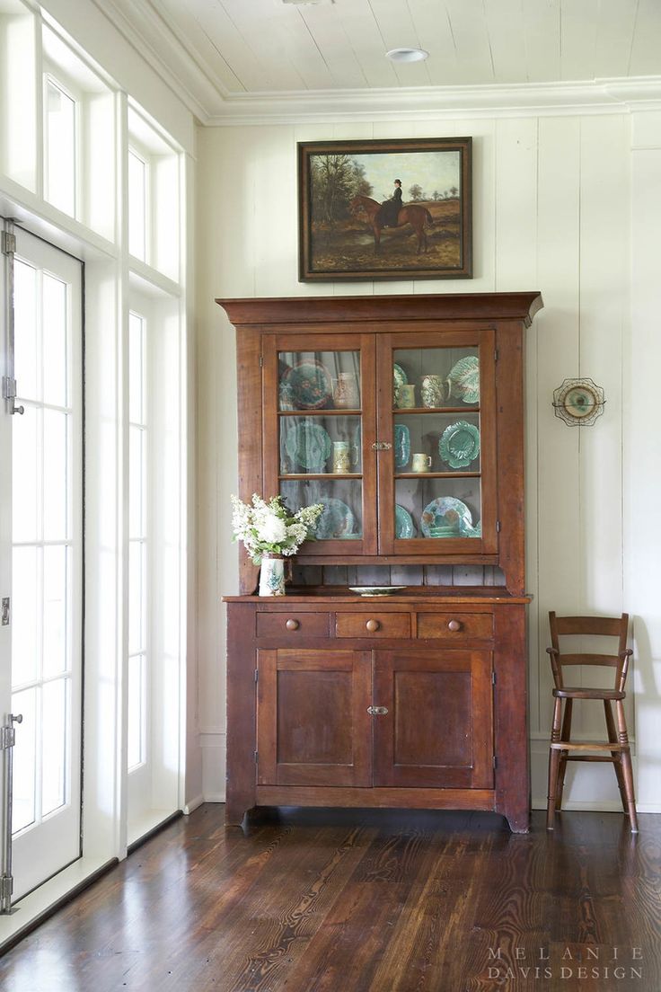 a wooden china cabinet sitting on top of a hard wood floor