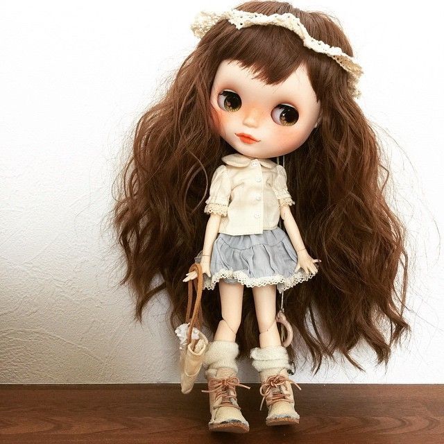 a close up of a doll with long hair on a wooden table next to a wall