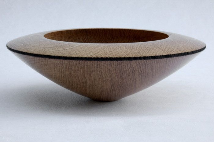 a wooden bowl sitting on top of a white table next to a black and brown object