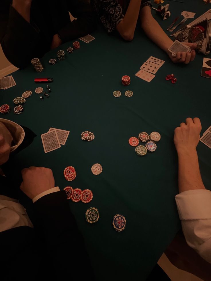 people sitting at a table with playing cards and casino chips on the table in front of them