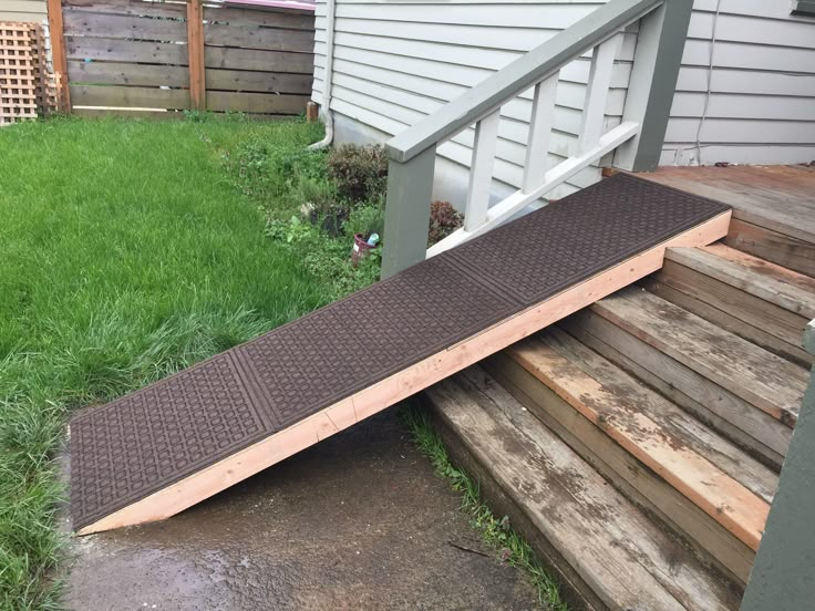 a wooden ramp sitting in the grass next to a house