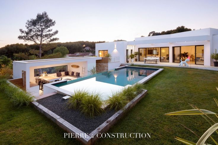 a house with a swimming pool in the middle of it's lawn and patio area