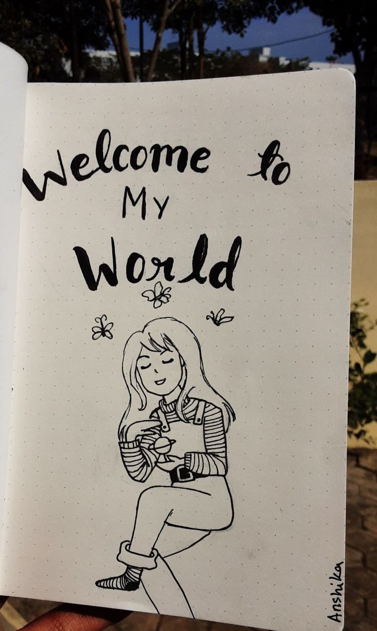 a hand holding up a notebook with the words welcome to my world written on it