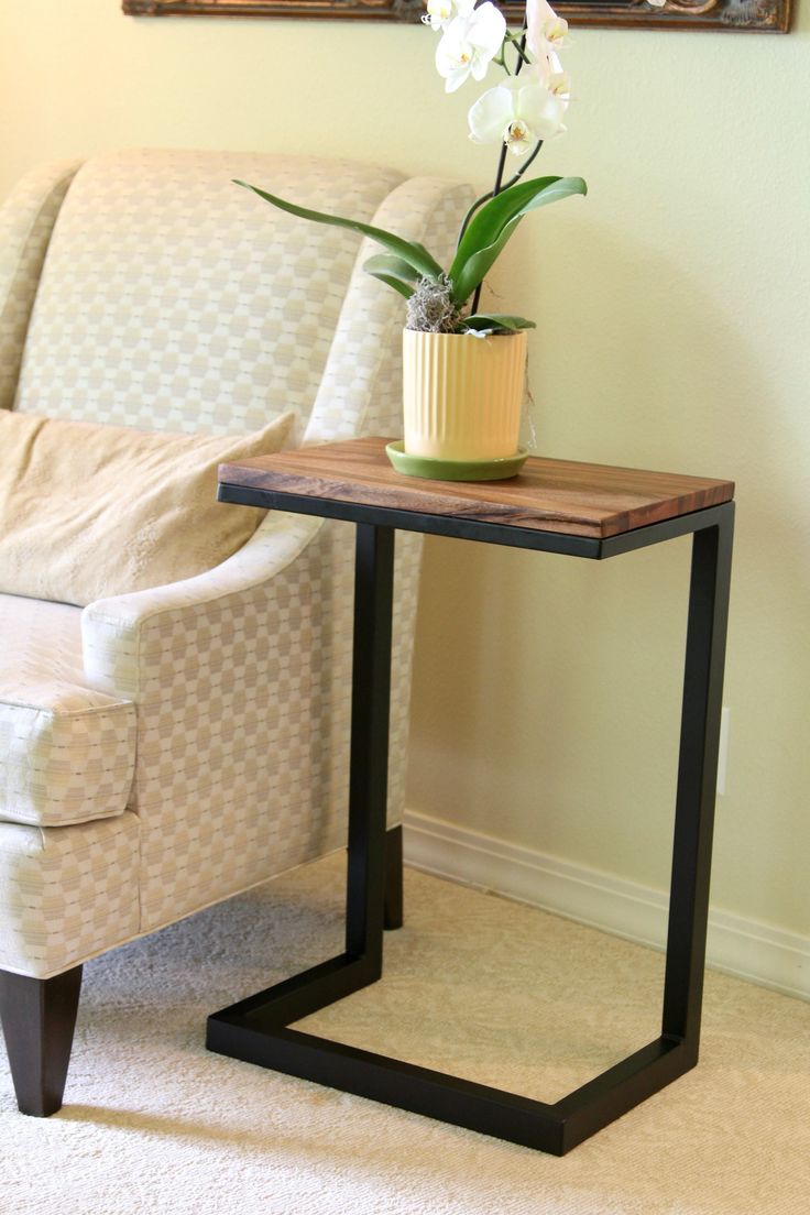 a small table with a potted plant on it in front of a couch and chair