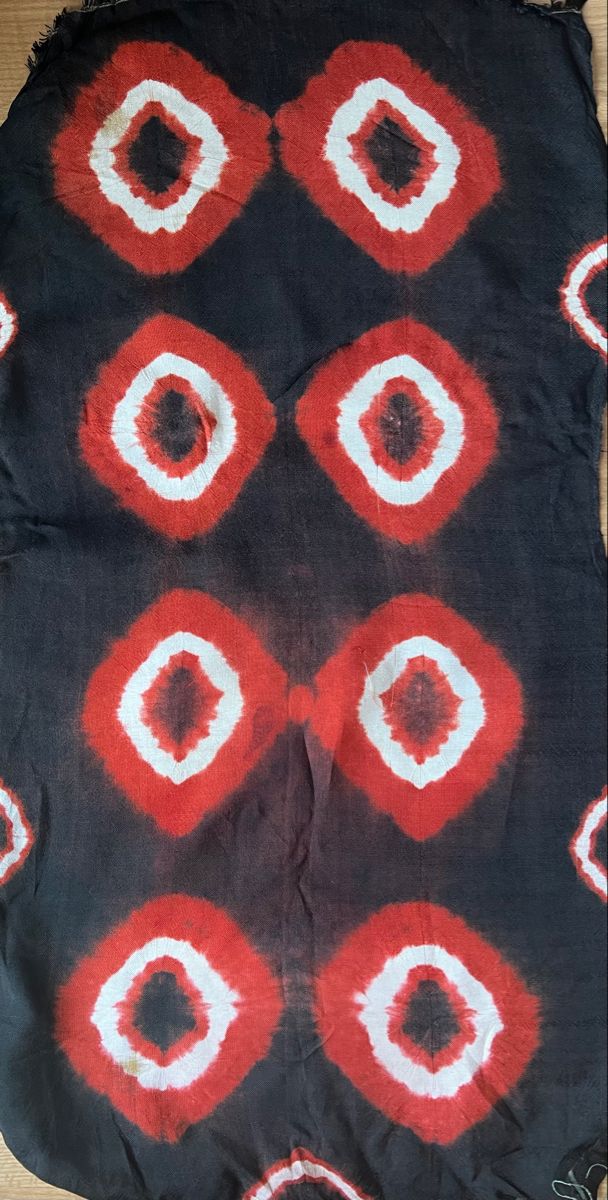 an old black and red cloth with white circles on the top, sitting on a wooden floor