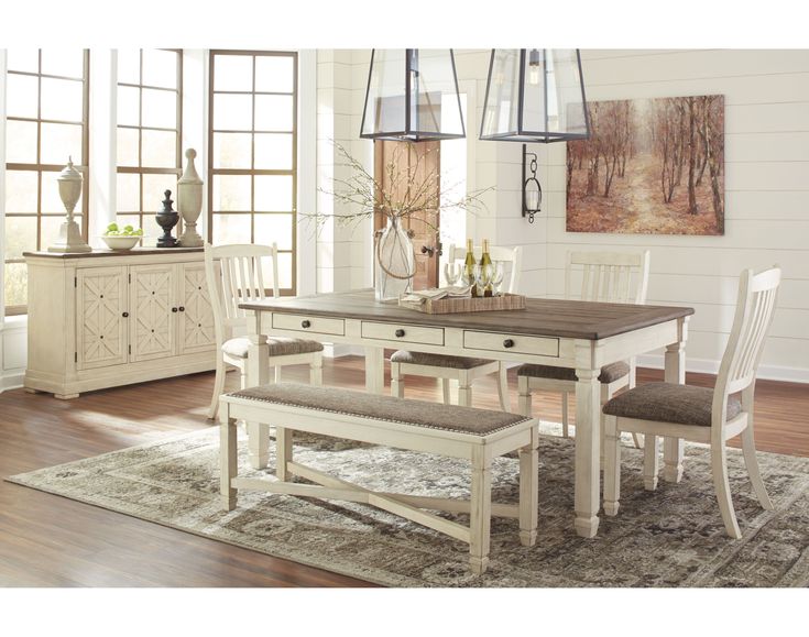 a dining room table with chairs and a bench in front of the window that has french country inspired decor on it