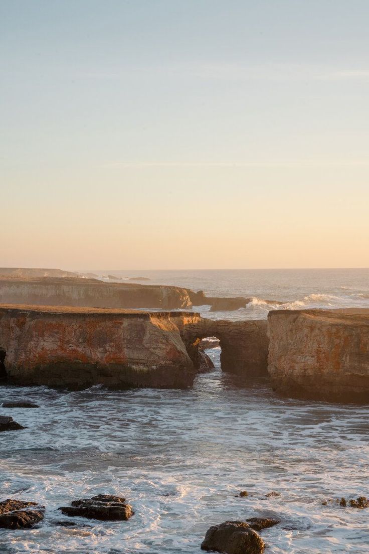 an ocean view with waves crashing on the rocks