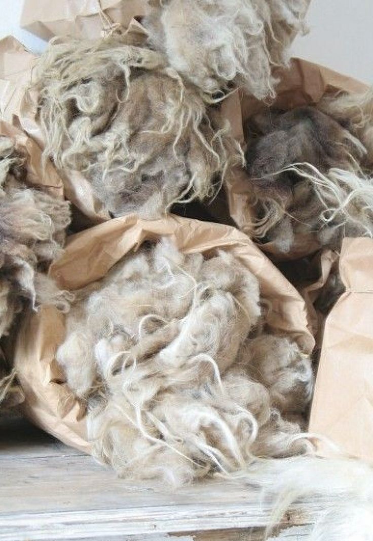 a pile of brown and white wool sitting on top of a wooden table next to a paper bag