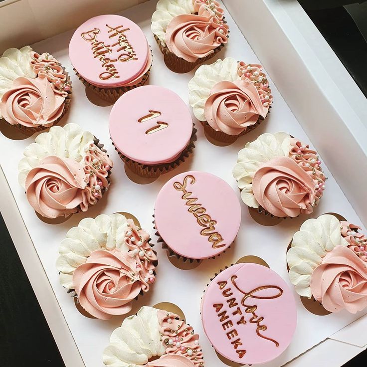 pink cupcakes with white frosting in a box that says happy 1st birthday