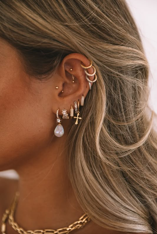 a woman with blonde hair wearing gold ear cuffs