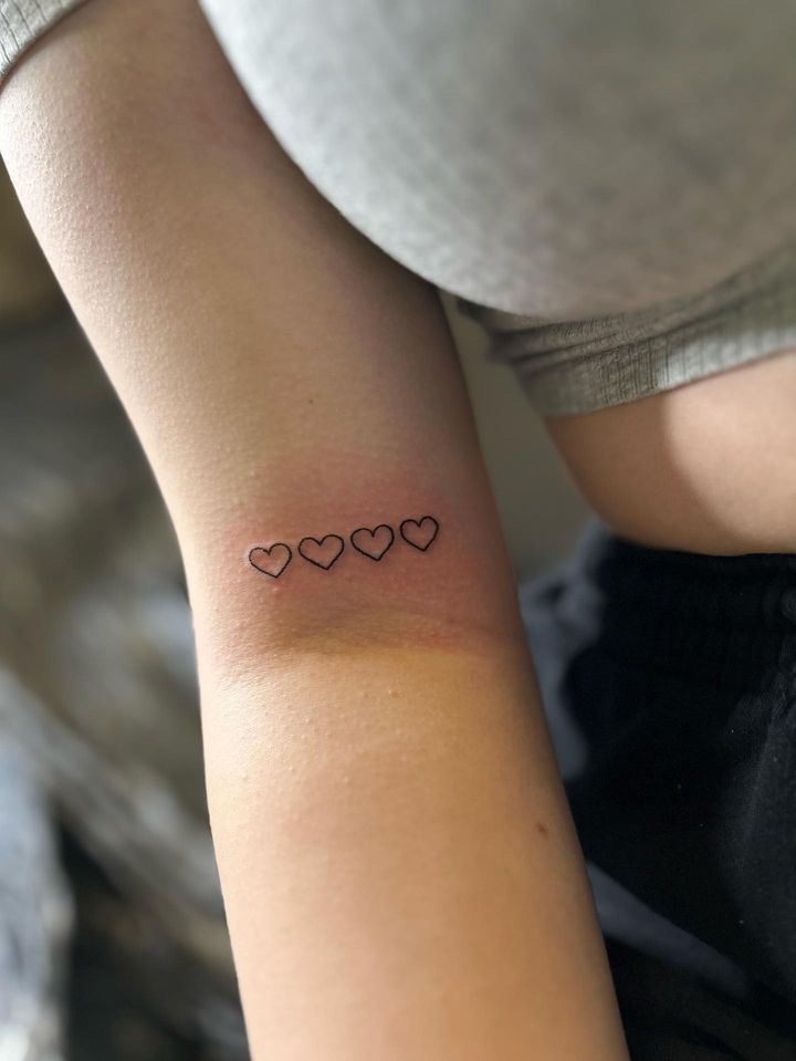 a woman's arm with three small hearts tattoo on the left side of her arm