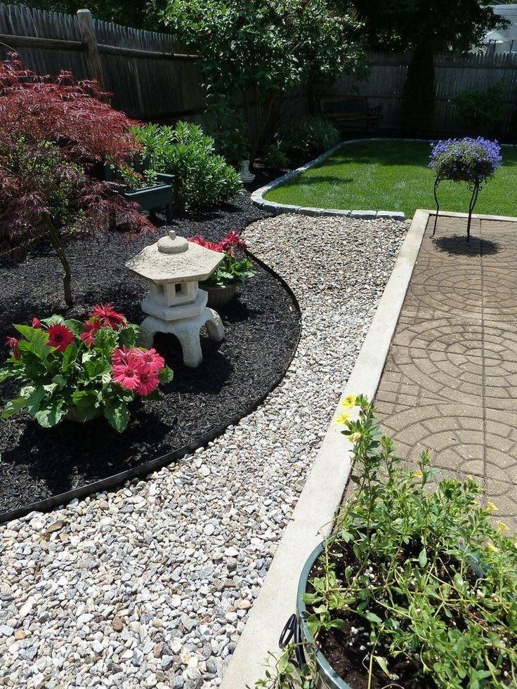 a garden with gravel, rocks and flowers