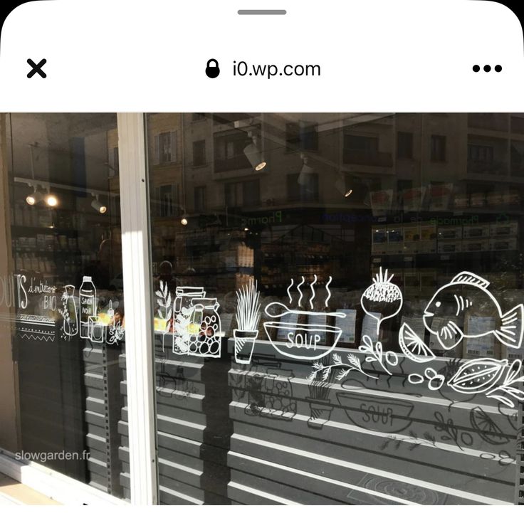 a window with some drawings on it in front of a store that sells food and drinks