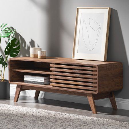 a living room with a wooden entertainment center and potted plant on the side table