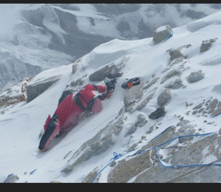 a man laying on top of a snow covered mountain