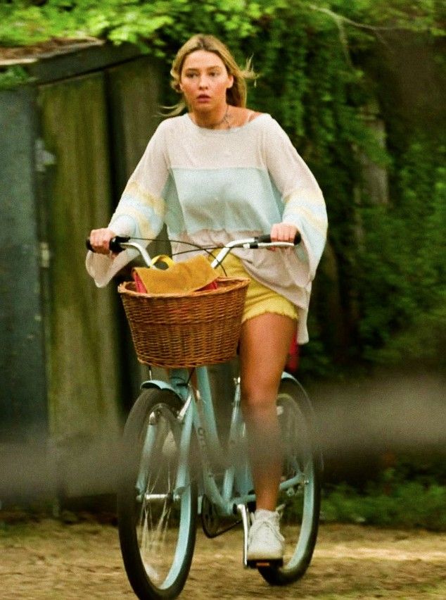 a woman riding a bike down a dirt road