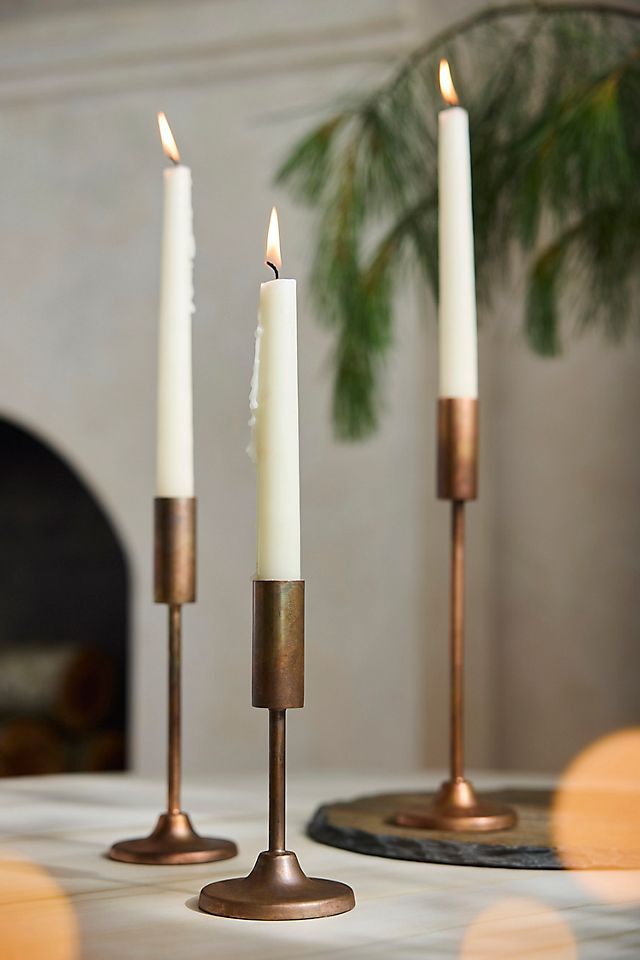 three candles sitting on top of a table next to a potted plant and fireplace