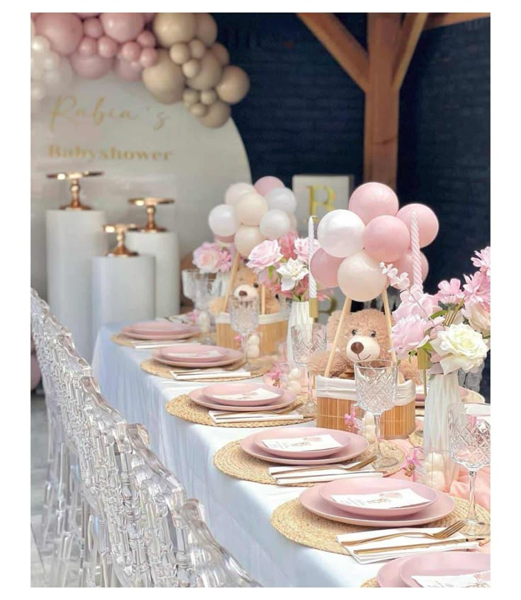 a table set for a baby shower with pink and gold decorations