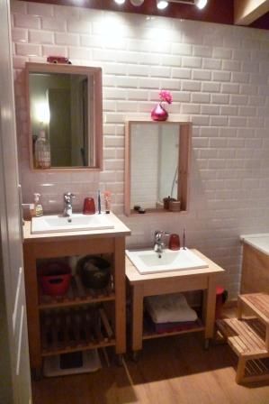 a bathroom with two sinks and a bathtub next to a brick wall in the corner