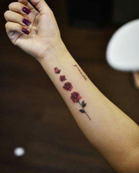 a woman's arm with red roses on it and the word love written in cursive writing