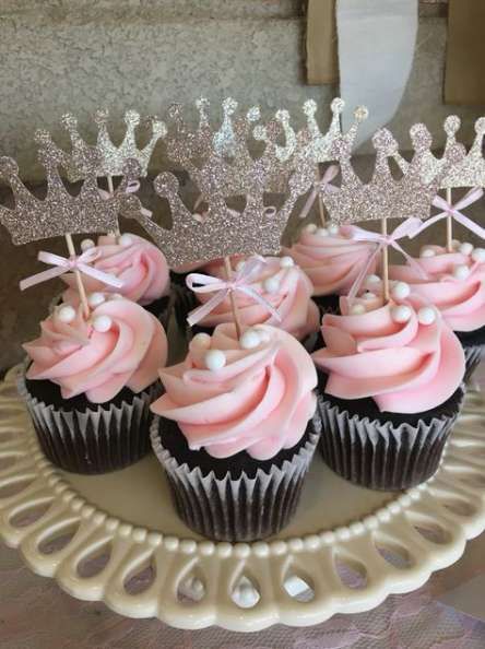 cupcakes with pink frosting and tiara decorations on a cake platter