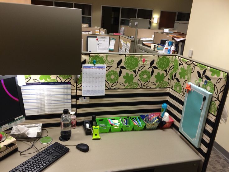 an office cubicle with desk, computer monitor and other items on the desk in front of it