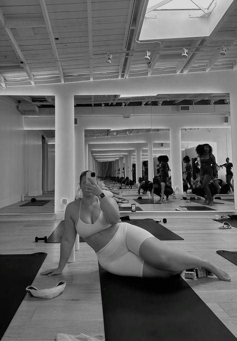 a woman is laying on her stomach in a yoga studio while taking a selfie