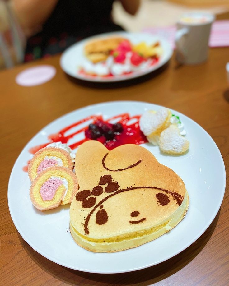 a plate topped with pancakes covered in frosting and cartoon characters next to other food items