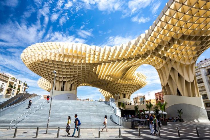 people are walking up and down the stairs in front of a large structure that looks like a fish