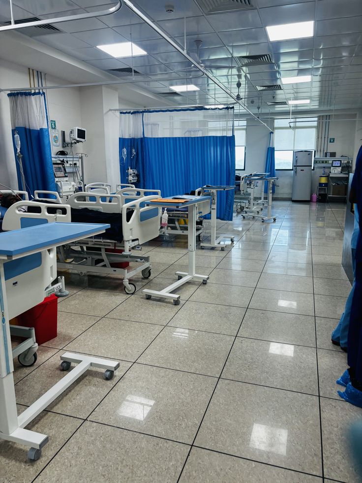 an empty hospital room with blue curtains and medical equipment on the floor in front of it