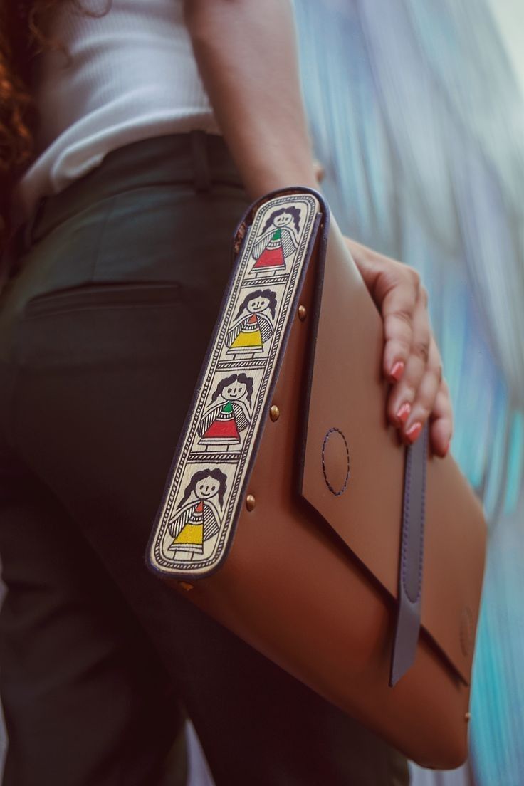 a woman holding a brown purse with designs on it