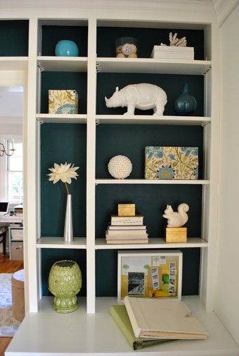 a bookshelf filled with lots of books and vases on top of it