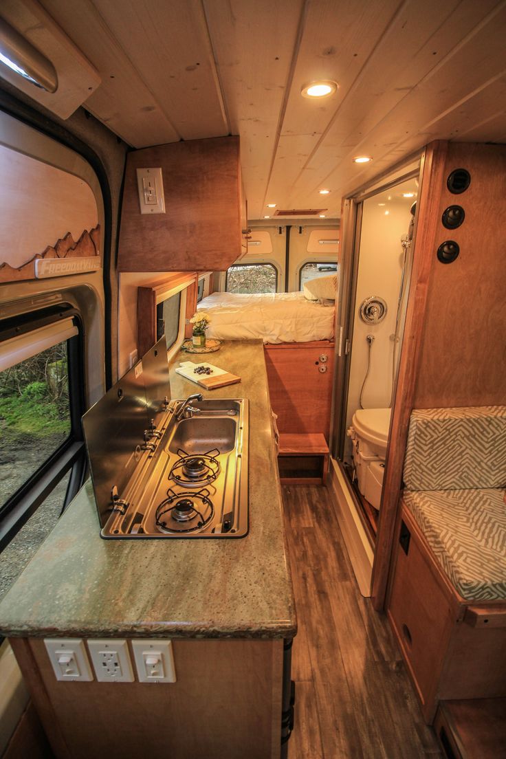 the kitchen and living area of an rv with wood flooring, counter tops and cabinets