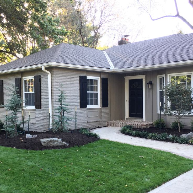 a house that has grass in front of it and bushes on the lawn behind it