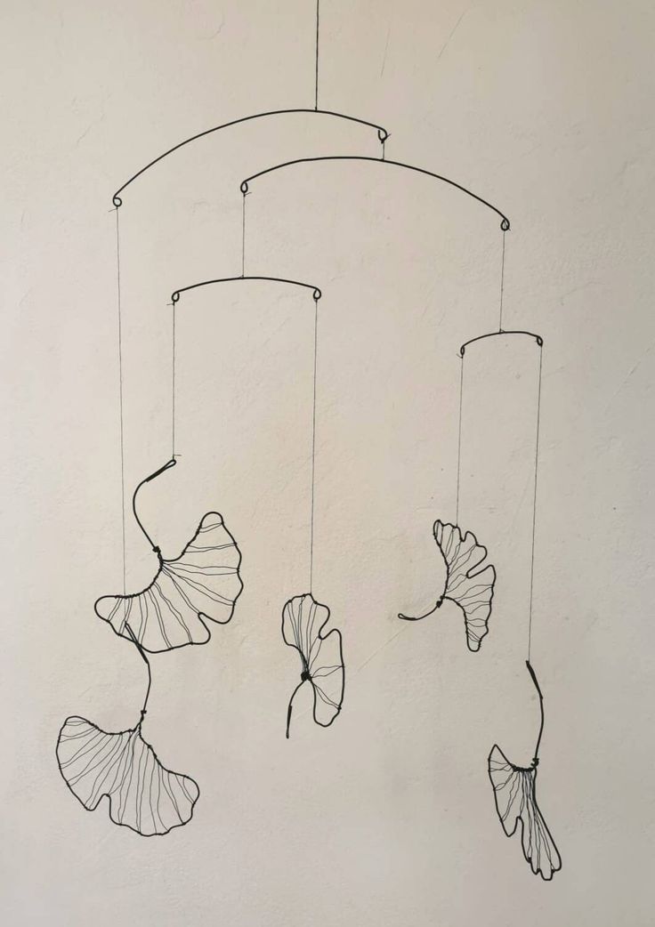 a drawing of three fish hanging from a string on the wall next to a white wall