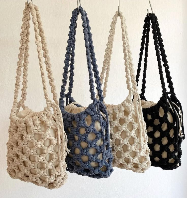 four crocheted purses hanging from hooks on a white wall, one is blue and the other is beige