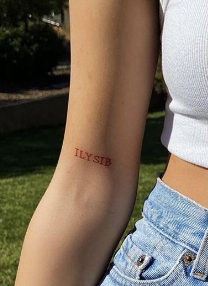 a woman with a small tattoo on her arm that says uyfsb in red ink