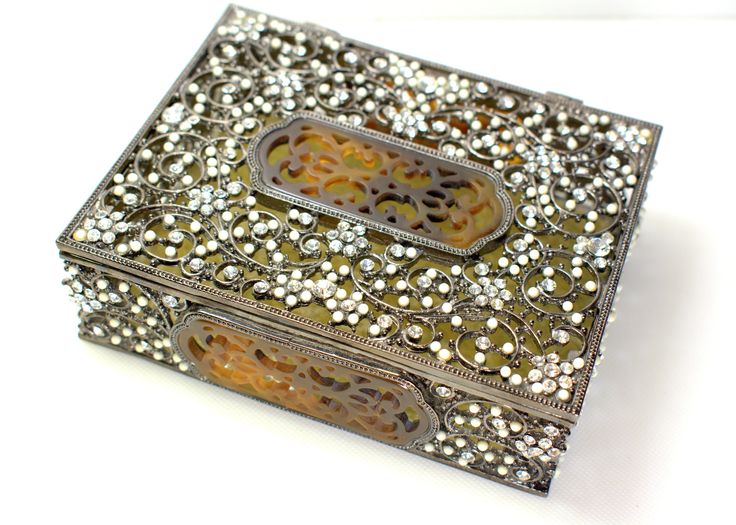 an intricately decorated box is shown on a white surface with beads and filigrees