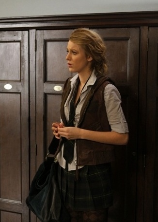 a woman standing in front of a wooden cabinet holding a purse and looking at something