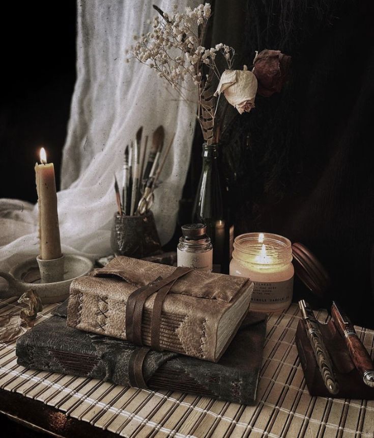 a table topped with books and candles next to a window