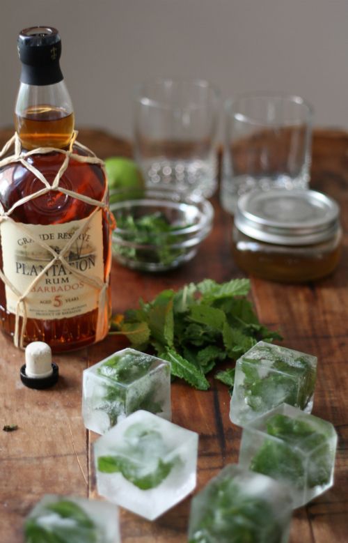 some ice cubes sitting on top of a wooden table next to a bottle of whiskey