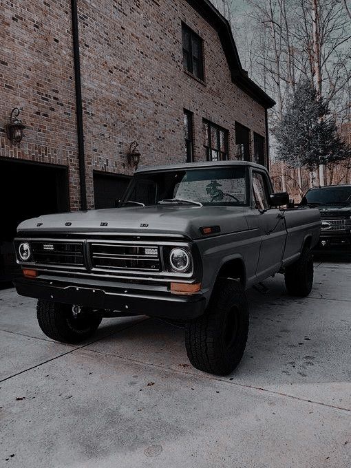 a green truck parked in front of a brick building