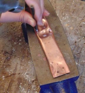 a person using a pair of scissors to cut metal parts on a piece of wood