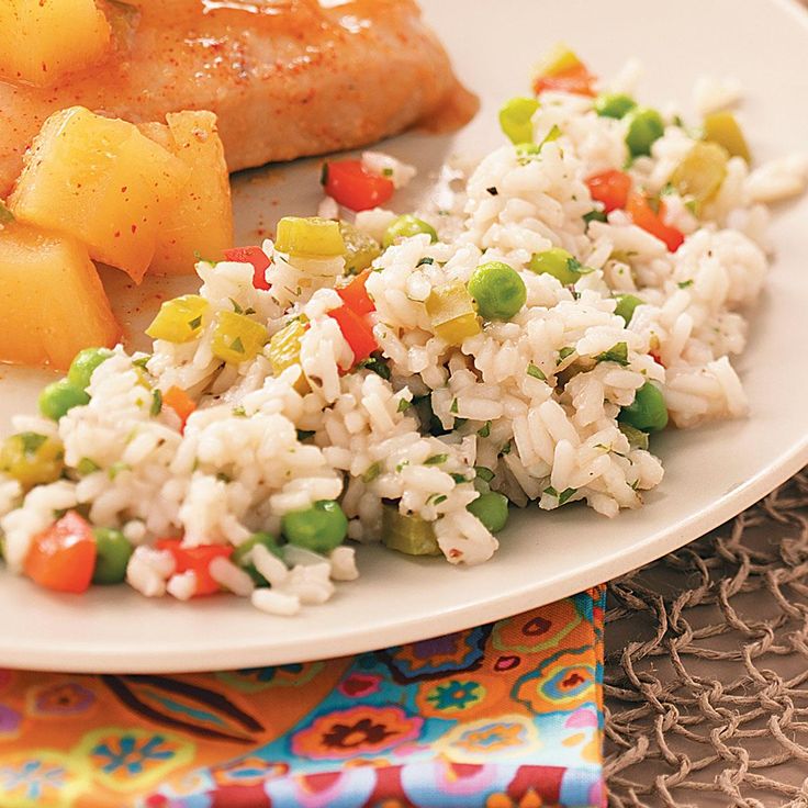 a white plate topped with rice and veggies next to meat on top of a table