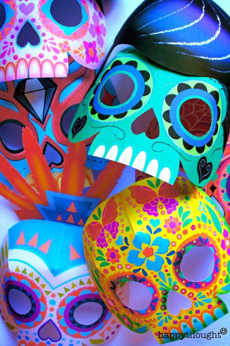 brightly colored sugar skull masks are stacked on top of each other, with one being cut out